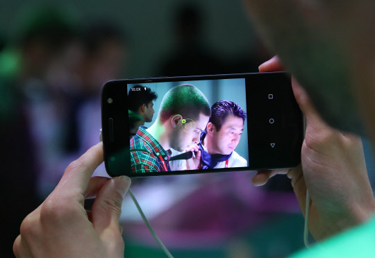 27일(현지시간) 세계 최대 모바일 전시회 '모바일 울드 콩그레스(MWC) 2017'이 열린 스페인 바르셀로나 피라 그란비아 내 모토로라 부스 내에서 행사 도우미가 핫셀블라드 카메라 모듈을 장착한 모토Z를 활용해 광학 10배 줌 촬영 시연을 해보이고 있다.      핫셀블라드 모듈을 사용하면 모토Z의 이미지 센서를 활용해 광학10배 줌과 LED 라이트를 사용할 수 있다. 또한 모토로라는 모토Z와 모토Z 플레이 용 JBL스피커, 핫셀블라드 카메라 모듈, 빔프레젝터를 선보였다.